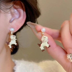 Detailed macro of dog pendant earring with white pearl and enamel coating on earlobe