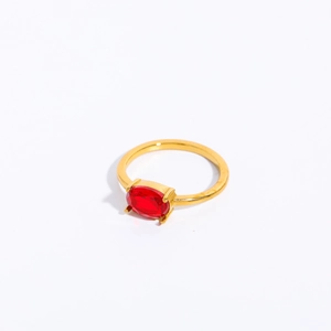 Close-up of golden stainless steel ring with a faceted oval red zircon birthstone inlay