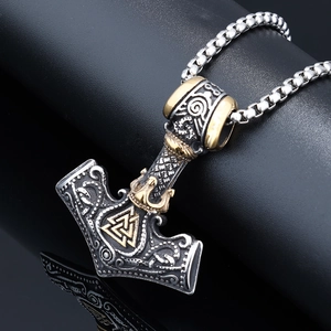 Macro detail of silver Mjölnir pendant with golden Valknut symbol and ornate engravings