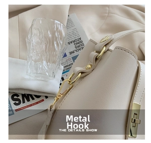 Close-up of golden metal hooks and adjustable buckle on a beige leather handbag