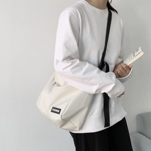 Canvas messenger bag in cream white showing model side profile and strap detail