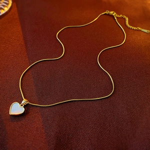Detail of gold heart pendant with mother of pearl inlay on a snake chain necklace