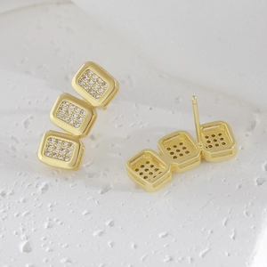 Minimalist gold geometric square stud earrings with cubic zirconia on textured background