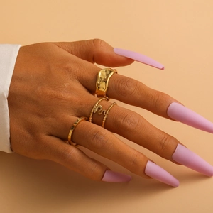 Close-up of three gold titanium rings layered on fingers with long pink matte nails