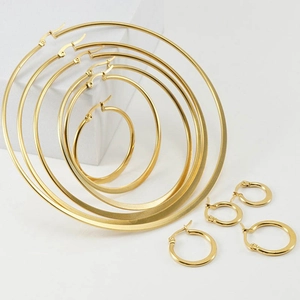 Set of nine golden stainless steel hoop earrings in various sizes on a white background