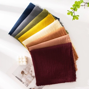 Close-up of cotton linen scarves in various colors with fringe edges and natural decor