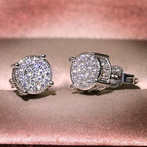 Macro detail of silver pavé-set zircon stud earrings displayed on pink satin fabric