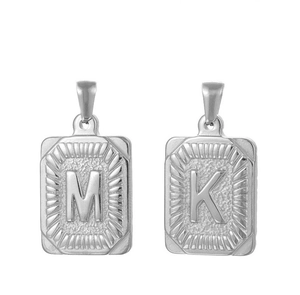 Macro view of silver rectangular pendants featuring engraved M and K letters