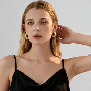 Golden textured hoop earrings with a twisted design worn by a female model