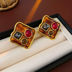 Détail de boucles d'oreilles vintage dorées avec résine ambre et gemmes colorées