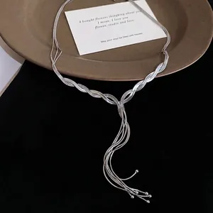 Silver multi-strand snake chain Y-necklace with elegant tassel pendant on a brown tray