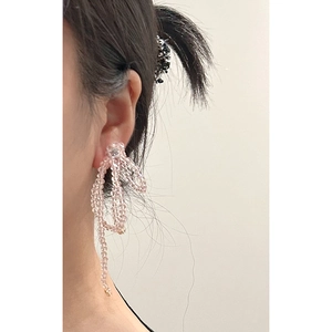 Pink beaded bow tassel earrings featuring a long hanging design worn by a model