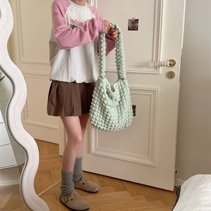 Detail shot of light green bubble textured canvas crossbody bag with soft pleated fabric