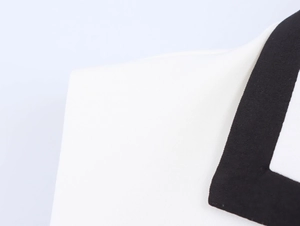 Gros plan détaillé du tissu blanc avec bordure noire contrastée et couture précise