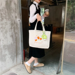 Lifestyle shot of a white quilted tote bag featuring floral and bunny embroidery detail