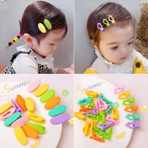 Matte candy-colored children hair clips in oval and hollow shapes set on a white plate