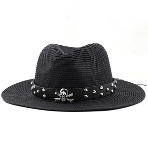 Macro detail of black straw fedora featuring a skull and rivet studded belt band