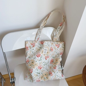Détail d'un sac cabas en coton à fleurs sur une chaise blanche avec étiquette en tissu