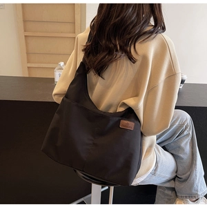 Close-up of black canvas tote bag showing the fashion leather patch and minimalist texture