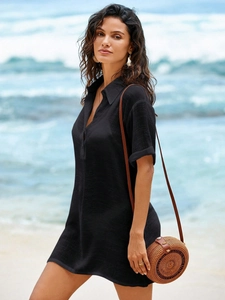 Relaxed black short sleeve linen shirt dress for women shown on a sunny beach setting