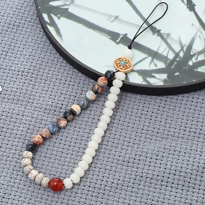 Detail of handcrafted bodhi seed phone strap with natural stones and white beads