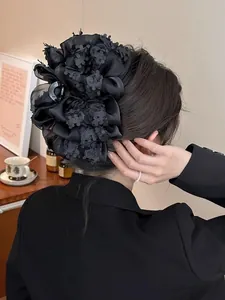 Détail d'une grande pince à cheveux fleurie en tissu noir avec paillettes élégantes