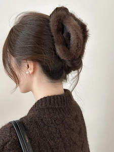 Détail d'une grande pince à cheveux en fausse fourrure marron foncé portée par un modèle