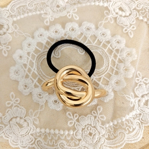 Close-up of a high-elastic black hair tie with a polished gold-finish knot metal detail