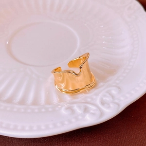 Macro shot of irregular wavy gold-plated ring with polished mirror surface and open design