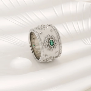 Vintage silver ring featuring an oval emerald green gemstone and intricate beadwork accents