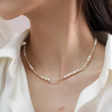 Detailed close-up of a delicate white natural pearl necklace worn on a female model