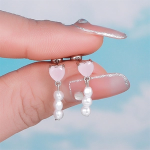 Macro view of pink heart earring with white pearl charms and silver metal details