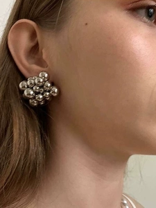 Primer plano de pendientes de racimo de bolas plateadas usados por una modelo real