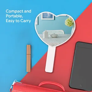 Minimalist white heart-shaped handheld makeup mirror with long handle on modern background