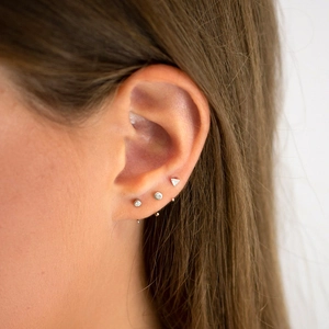 Close-up of minimalist S925 silver geometric stud earrings worn on a female ear model
