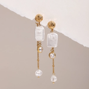Detail of gold earrings with hammered studs, baroque pearls, and zircon tassels