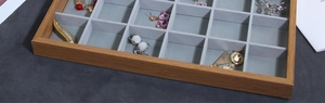 Macro shot of partitioned wooden jewelry tray with gray velvet lining for rings and earrings