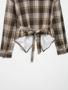 Détail d'une chemise à carreaux marron à manches longues avec nœud au dos et ourlet superposé