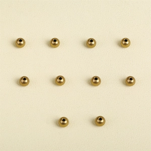 Ten round antique brass spacer beads for DIY jewelry making on textured background