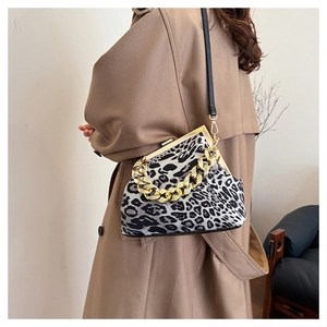Detail of leopard print shell bag with golden chain and clasp on a trench coat