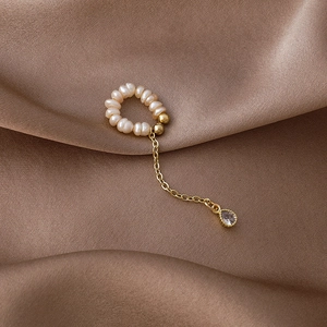 Detail of freshwater pearl ear cuff featuring a gold tassel with a teardrop zircon pendant