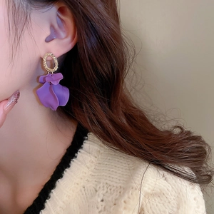 Close-up of purple petal earring with golden textured metal ring on ear