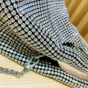 Macro shot of silver rhinestone bucket bag showing sparkling crystals and metal chain hooks