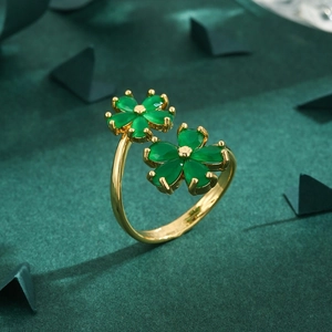 Elegant gold ring featuring green gemstone flower charms on a deep green velvet surface