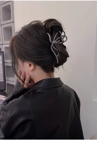 Silver butterfly metal hair claw clip worn by a model in a minimalist modern setting