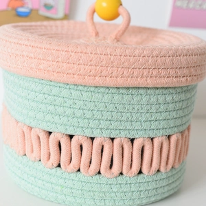 Detail of woven cotton rope storage basket with lid in mint green and coral pink