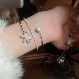 Close-up of a luxury gold cuff bracelet with sparkling zircons and a white pearl detail