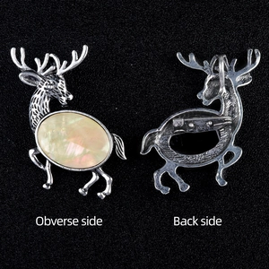 Silver elk brooch with beige crystal inlay, front and back view on dark textured background