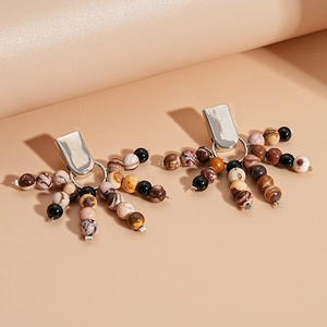 Detail of silver clip-on earrings with multicolored stone beads and marbled patterns