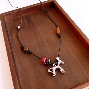 Détail de perles en œil de tigre et pendentif cheval argenté sur plateau en bois